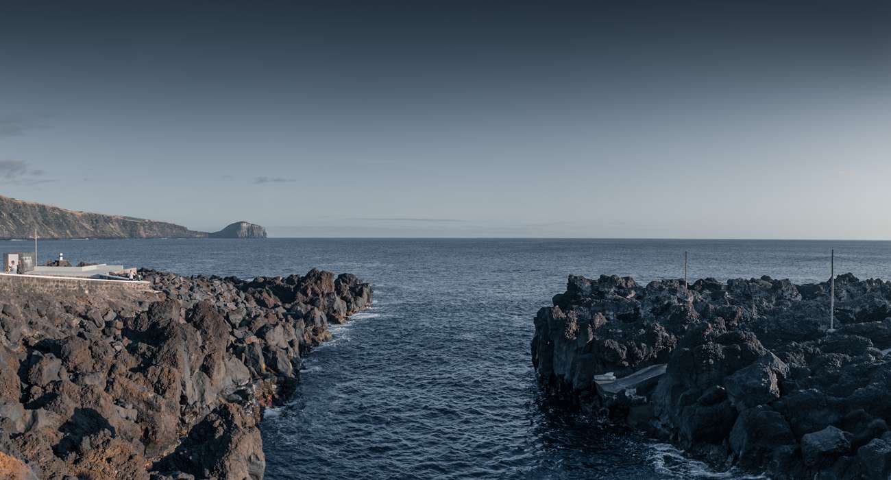 Channel between lava walls at the Varadouro sea pools in the last light, Faial, Azores