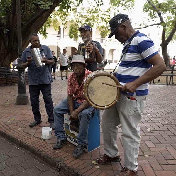 Street musicians with accordion, drum and güira playing on a pavement in Santo Domingo, Dominican Republic