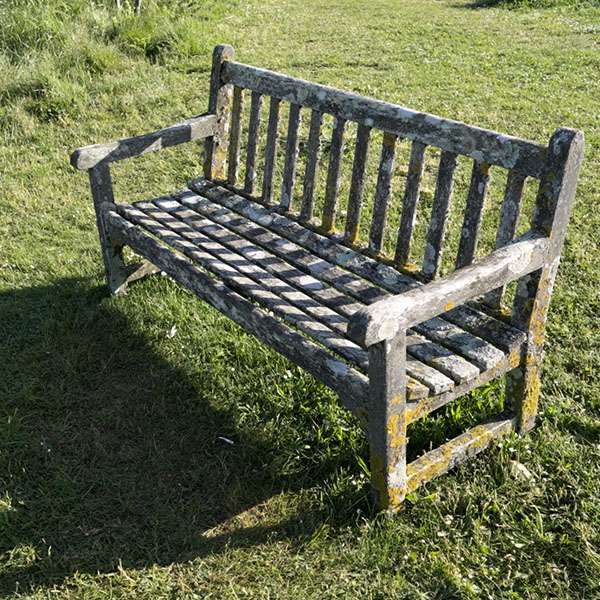 Weathered wooden bench on a lawn in Hugh Town, St Mary's, Isles of Scilly, England
