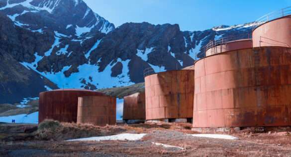 Rusting oil tanks of the abandoned whaling station at Grytviken below snow-covered mountains, South Georgia