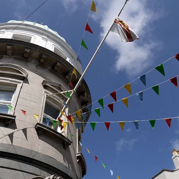 Bunting strung from a lamp post in front of a granite tower in Saint Peter Port, Guernsey