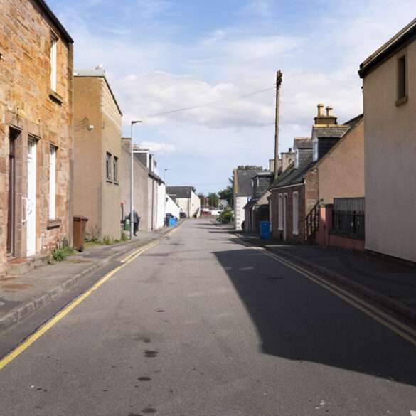 Quiet main street of Invergordon with stone houses in morning light, Scottish Highlands