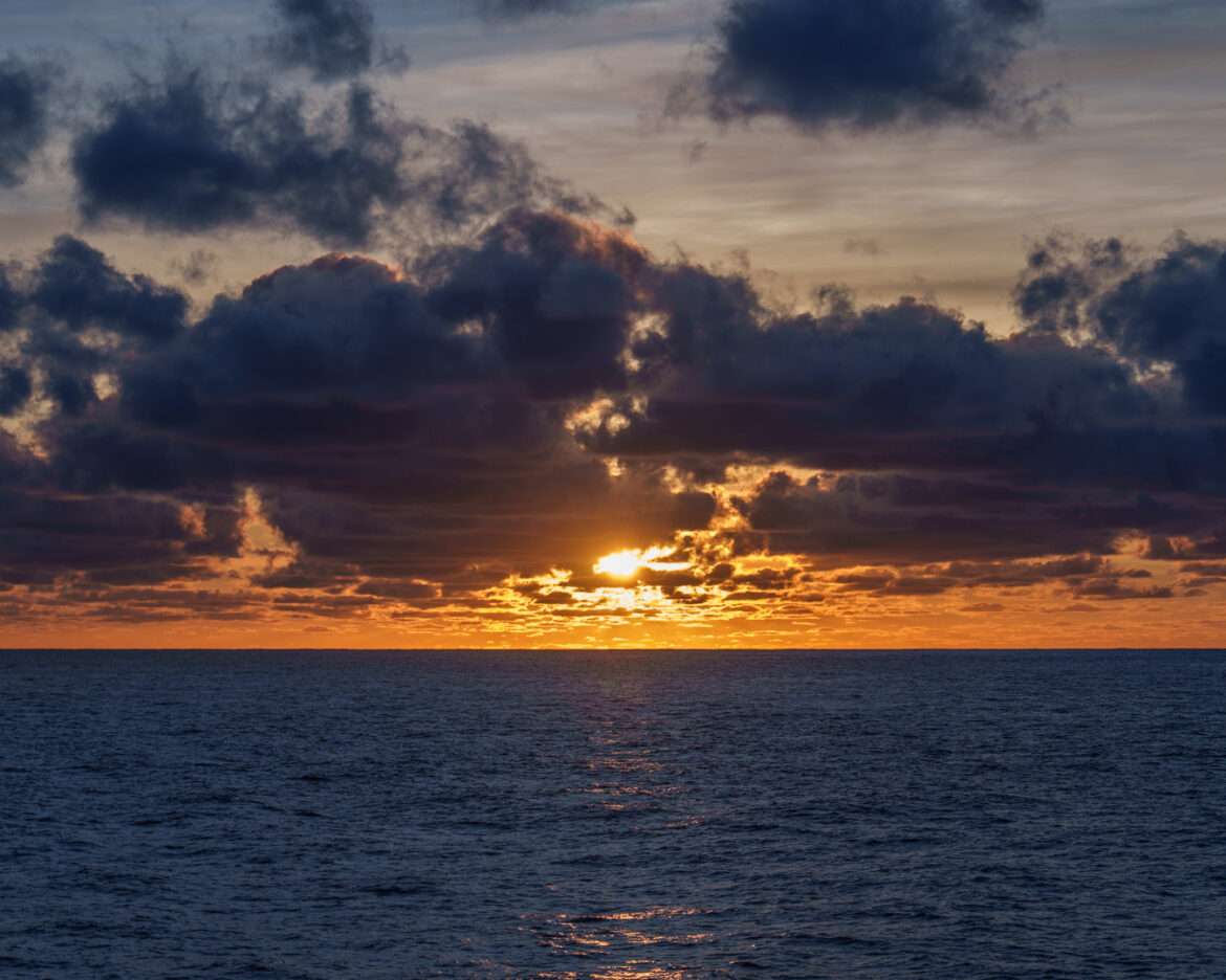 Sunset breaking through cloud over the open Atlantic, seen from a ship