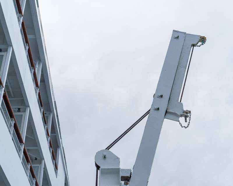 White superstructure and a davit arm against an overcast sky at sea