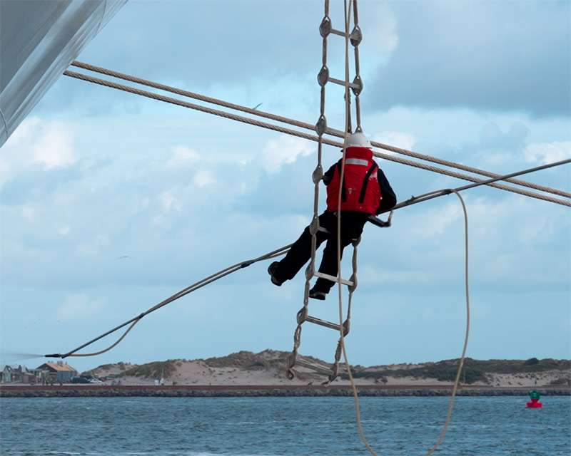 A sailor doing paintwork on the ship in the port of IJmuiden before the excursion