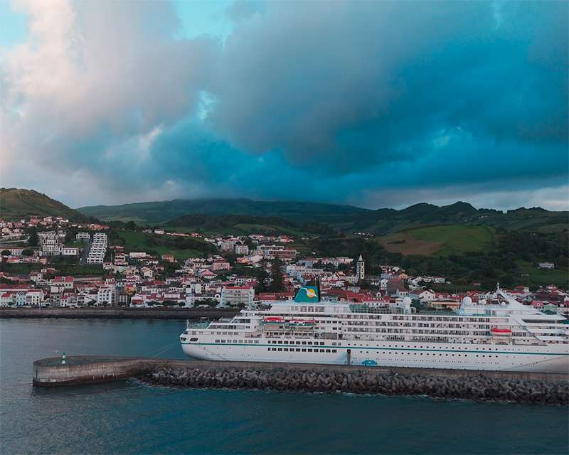 Cruise ship alongside the breakwater at Horta with the town and green hills behind, Faial