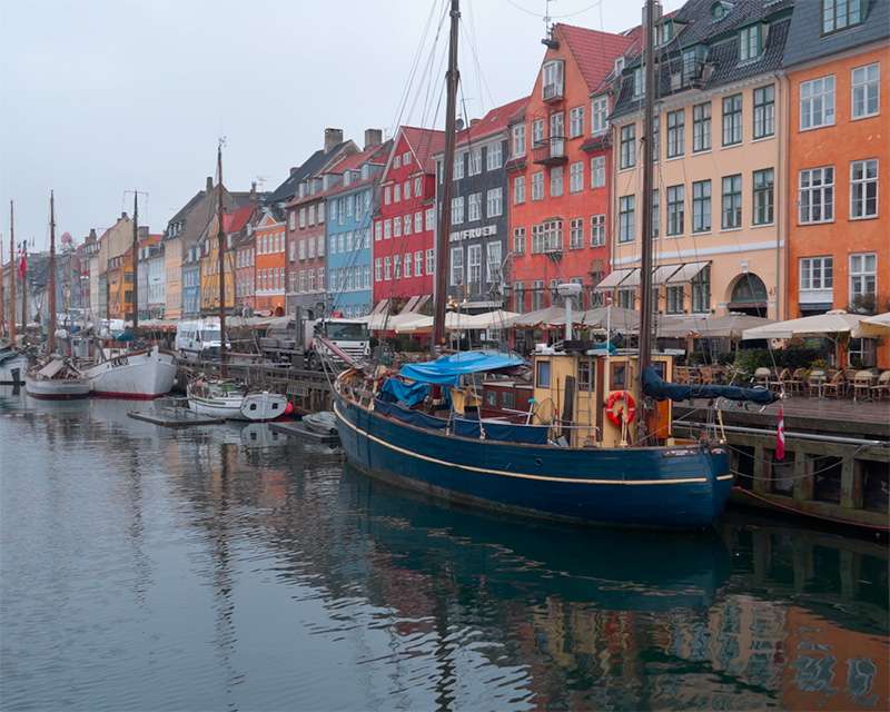 Wide view along the Nyhavn canal with painted house fronts and moored boats