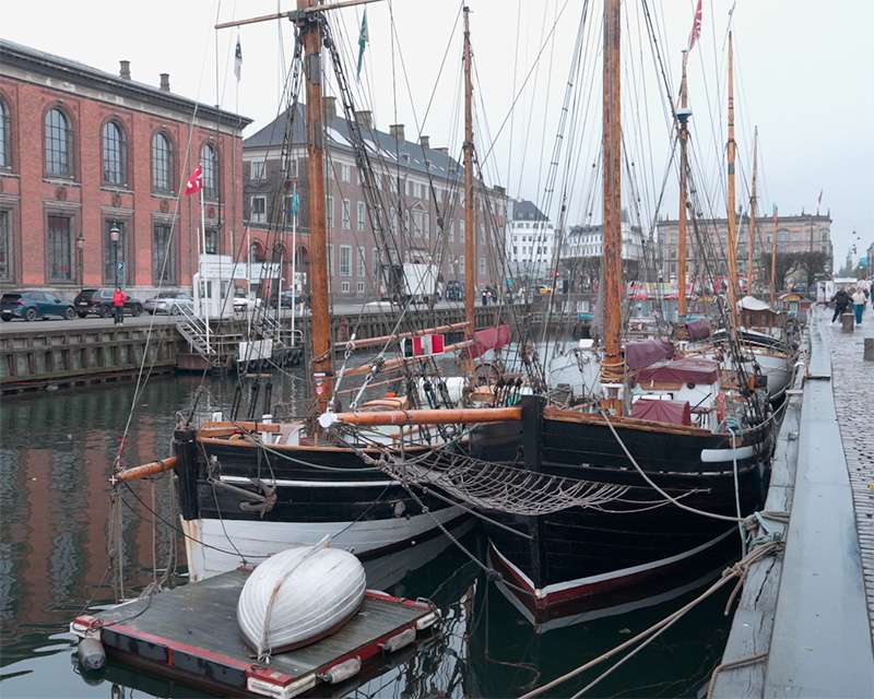 Historic wooden sailing ships moored along the quay at Nyhavn, Copenhagen