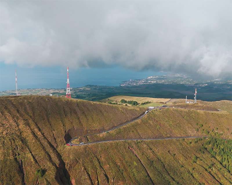 Cloud rolling over the green ridge of the Serra de Água de Pau with transmitter masts on the summit, São Miguel