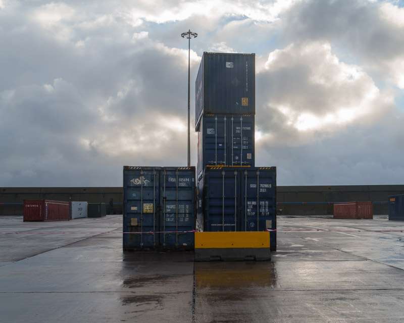 Stacked shipping containers on the wet commercial quay at Praia da Vitória, Terceira