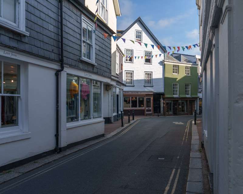 Bunting strung across a street in Totnes, white-fronted shops and houses on both sides