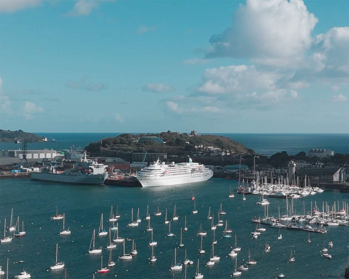 Cruise ship alongside Falmouth Docks seen from the air, with yacht moorings and the Pendennis headland