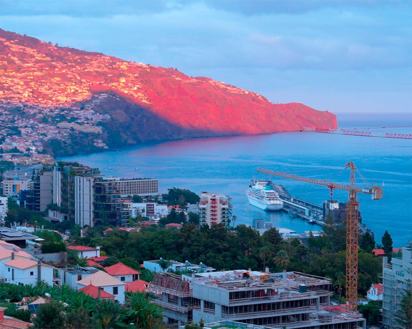 View from Miradouro da Nazare across Funchal bay to the cruise ship and the red-lit cliffs