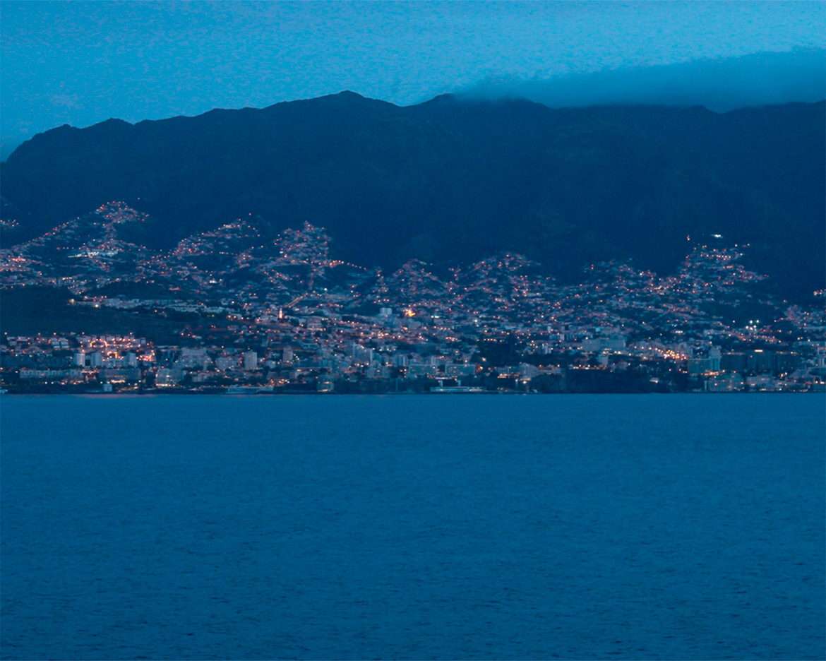 Funchal lit up on its hillside before sunrise, seen from the approaching ship