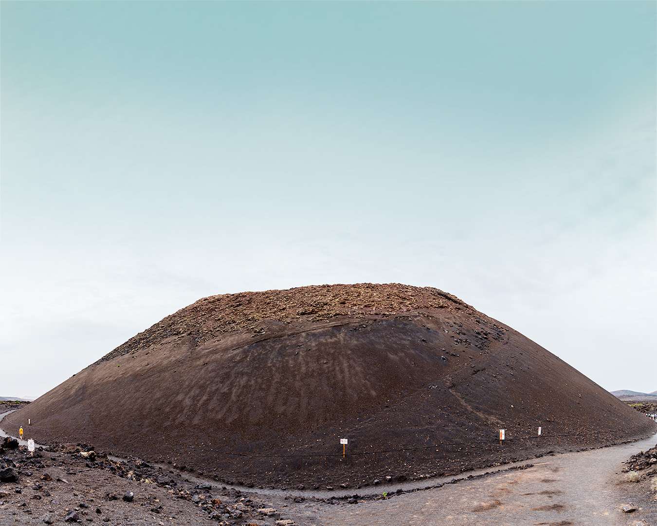 The low cone of Caldera de los Cuervos on Lanzarote with walkers on the track below it