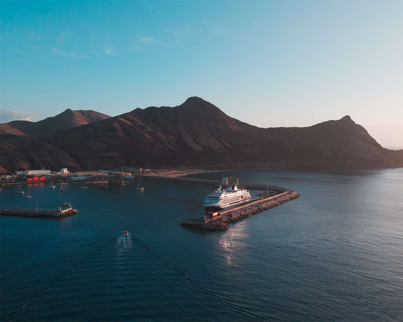 Hafen von Porto Santo im ersten Licht, ein Schiff an der Mole und ein Tenderboot in der Bucht