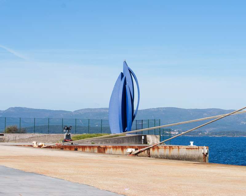 Blue steel sculpture on the waterfront promenade at Vilagarcía de Arousa, with the Ría de Arousa behind
