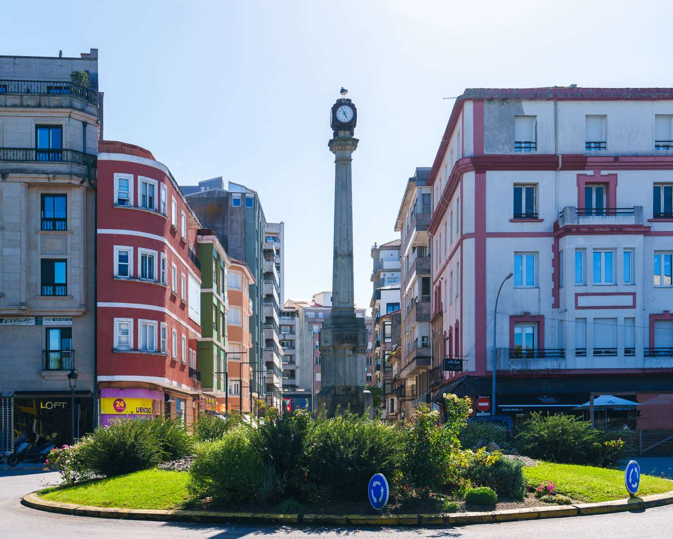 Clock column on a roundabout in central Vilagarcía de Arousa, surrounded by painted apartment buildings