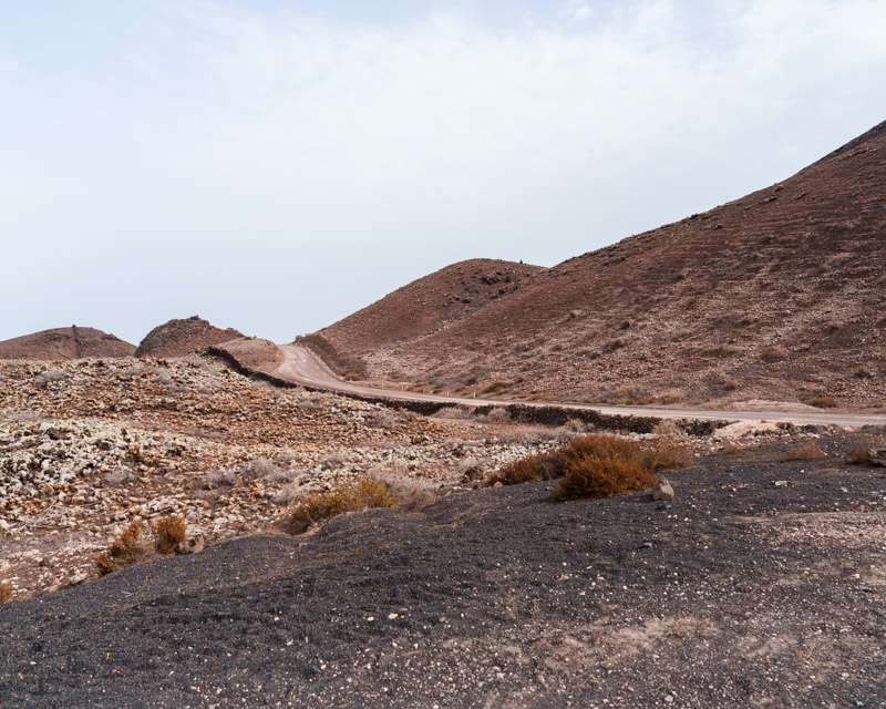 Track through the Malpaís lava field below a cone of the Bayuyo chain, Fuerteventura