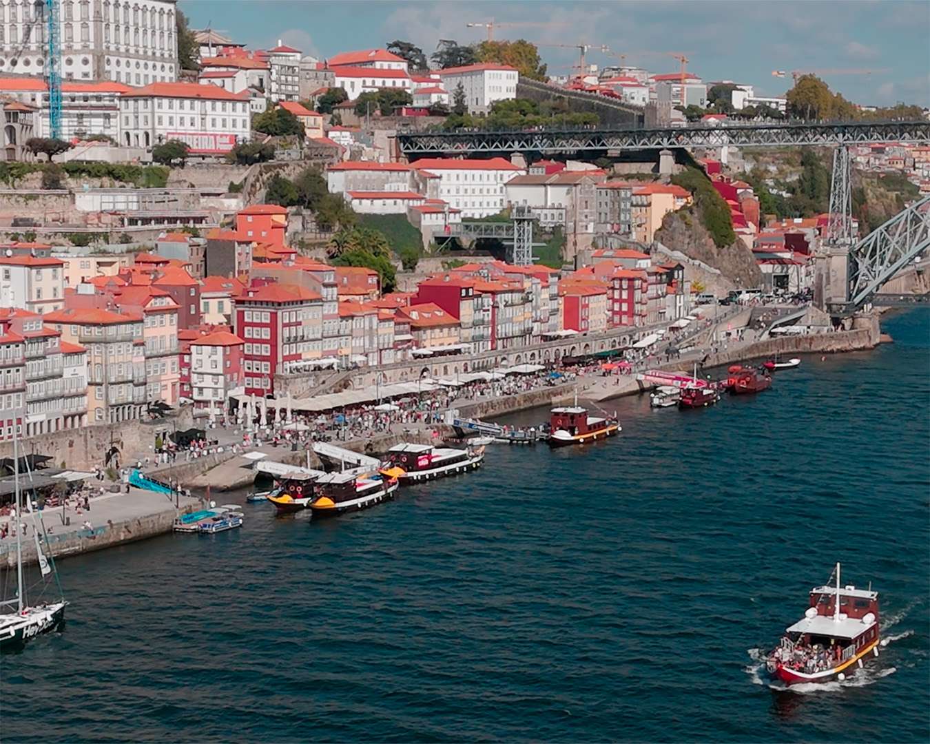 The Ribeira waterfront in Porto with tour boats moored below the Lu&iacute;s I bridge