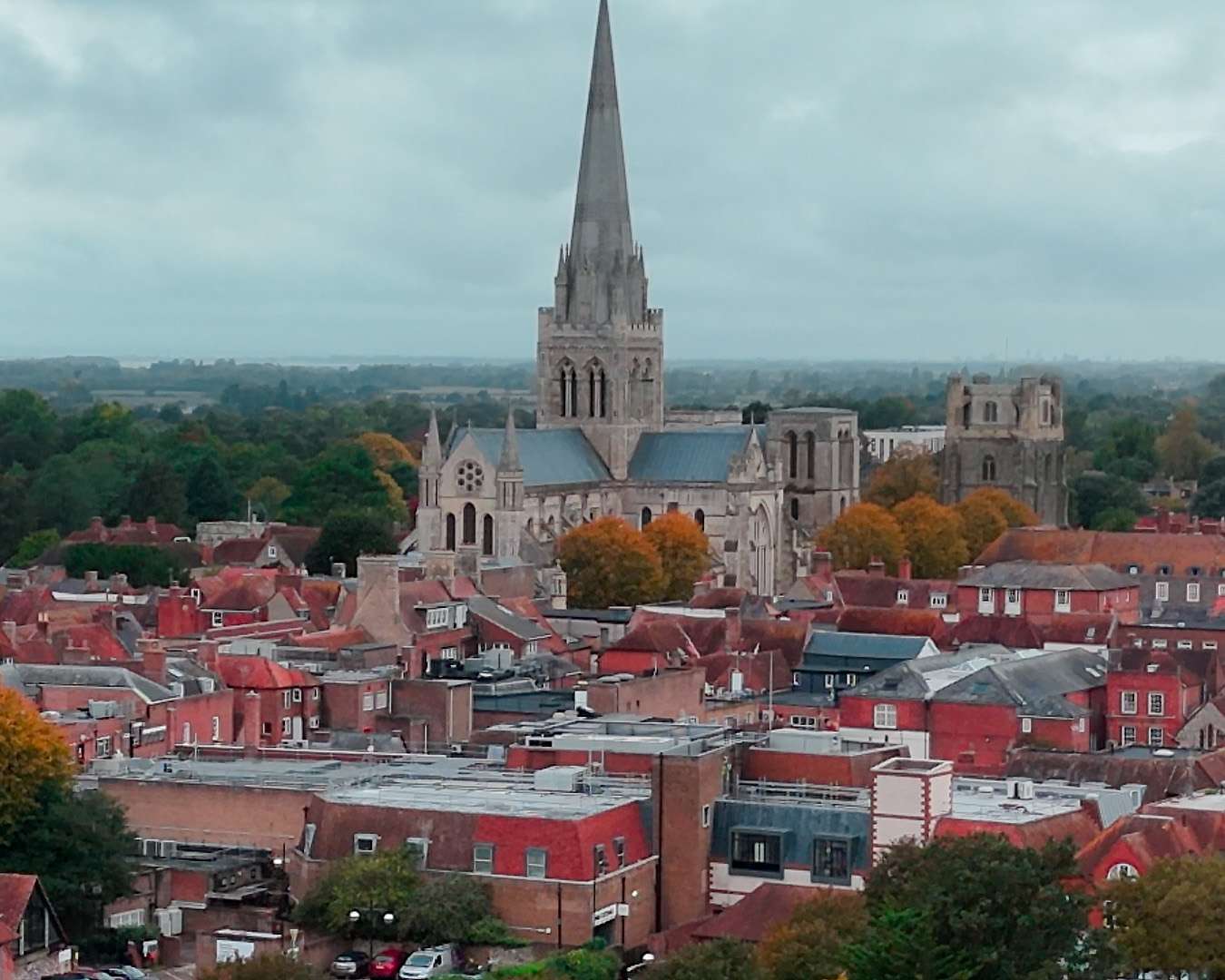 Aerial view of Chichester with the cathedral spire above the red roofs in autumn