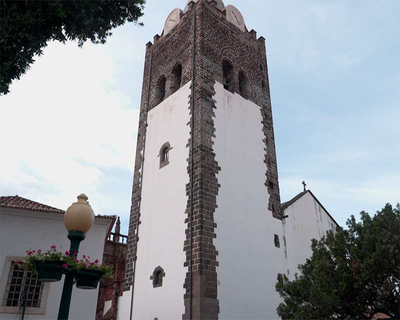Basalt-cornered bell tower of Funchal Cathedral rising above the old town rooftops
