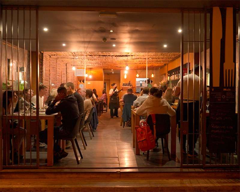 View through the open front of a busy restaurant in Funchal old town in the evening