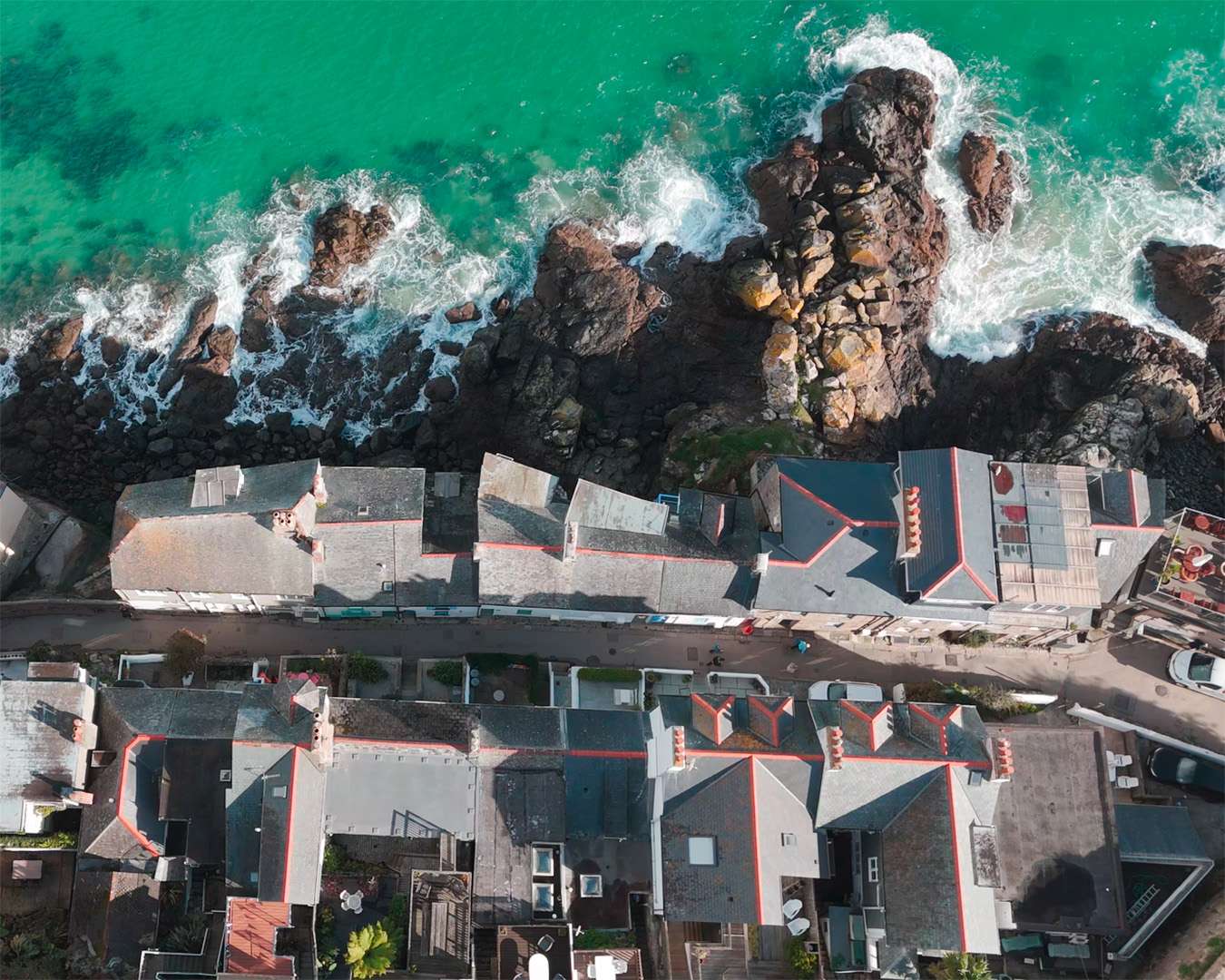 Rooftops of the Downalong quarter at the water's edge in St Ives with surf on the rocks