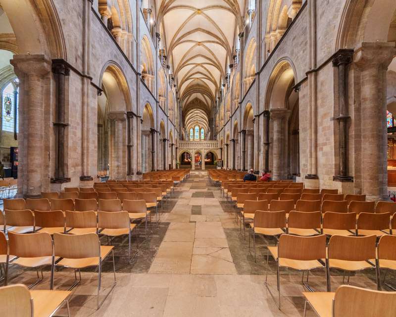 The nave of Chichester Cathedral with rows of chairs under the stone vault
