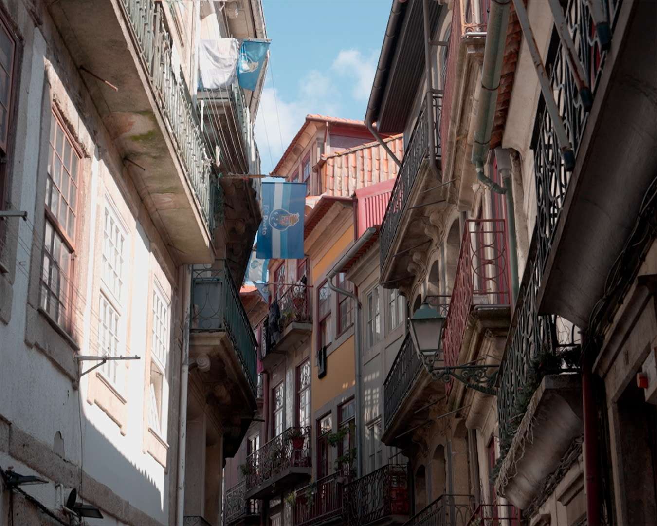 Enge Gasse in der Altstadt von Porto mit Balkonen und einer blauen Fahne zwischen den H&auml;usern