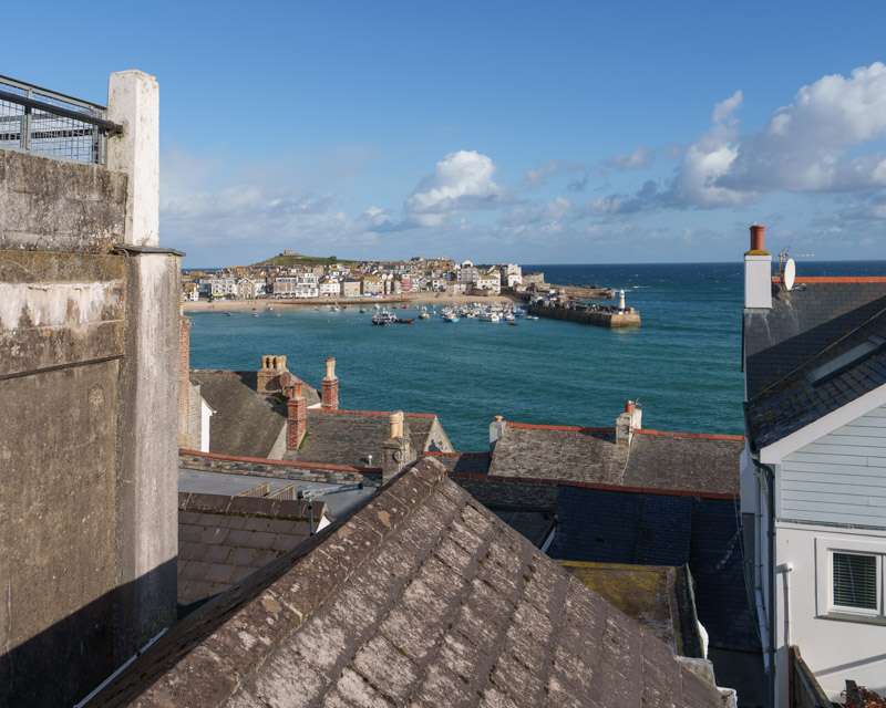 View over the roofs of St Ives to the harbour wall and the open sea