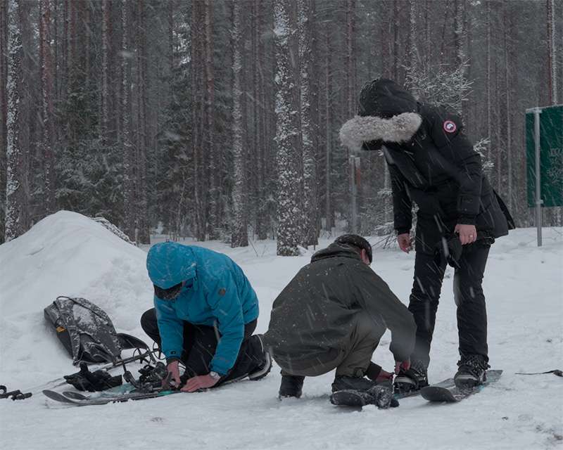 Visitors strapping on snowshoes at the start of the Pilpasuo nature trail near Oulu