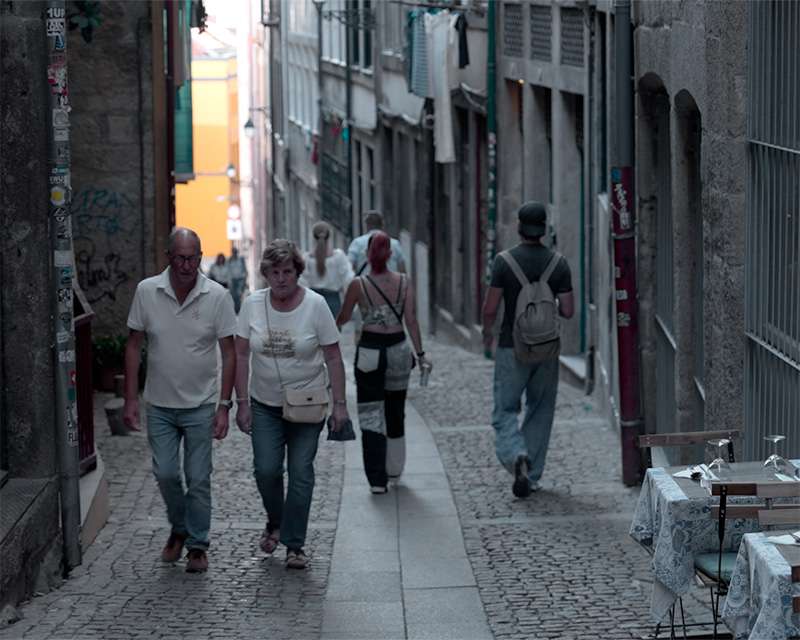 Spazierg&auml;nger in einer schmalen Altstadtgasse von Porto mit bemalten Hausw&auml;nden