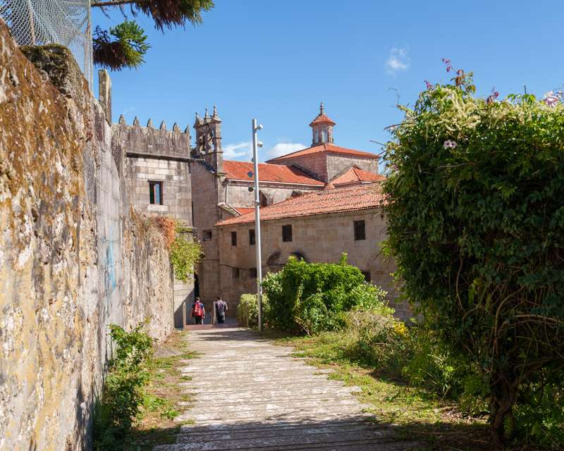 Cobbled lane climbing to the Vista Alegre convent between a stone wall and greenery, Vilagarcía de Arousa