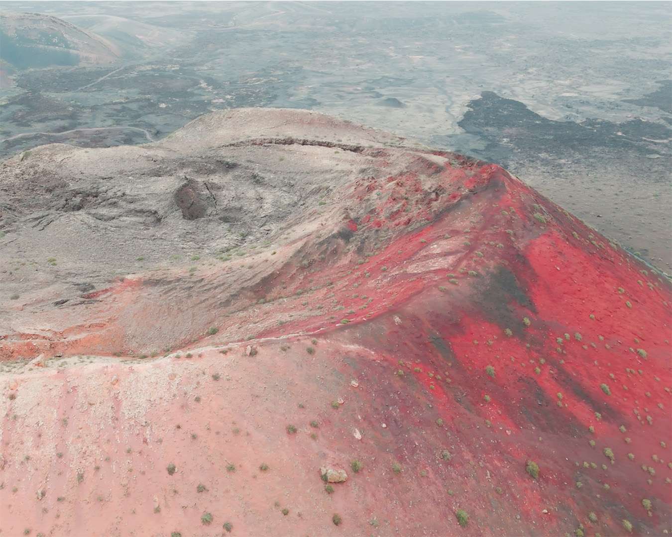 Montaña Colorada from the air, a red crater set in the black lava field of Lanzarote