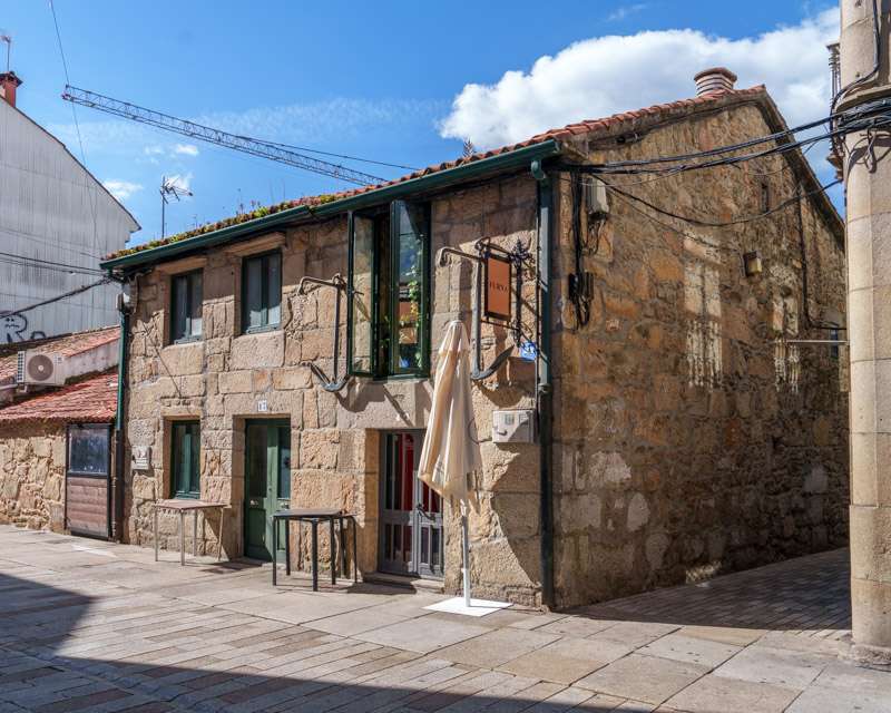 Old granite fishermen's house in Vilagarcía de Arousa with a construction crane rising behind it