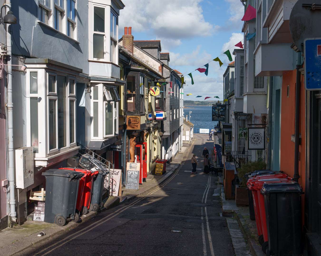 Steep narrow street in Falmouth old town with bunting overhead and the harbour visible at the lower end