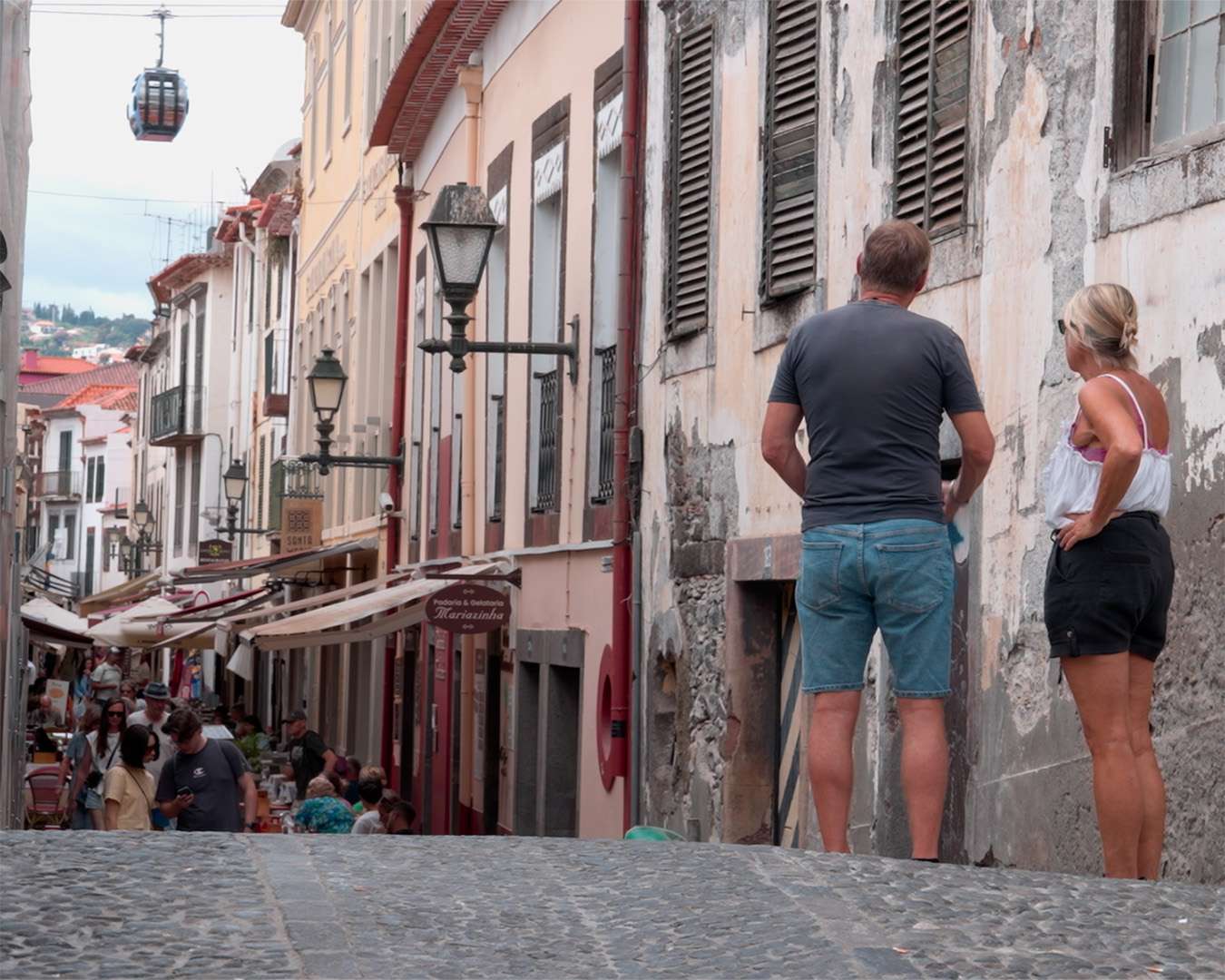 Cobbled Rua de Santa Maria in Funchal's old town with visitors at the painted doors