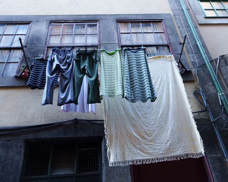 W&auml;sche h&auml;ngt zum Trocknen vor einem Fenster in einer Altstadtstra&szlig;e von Porto