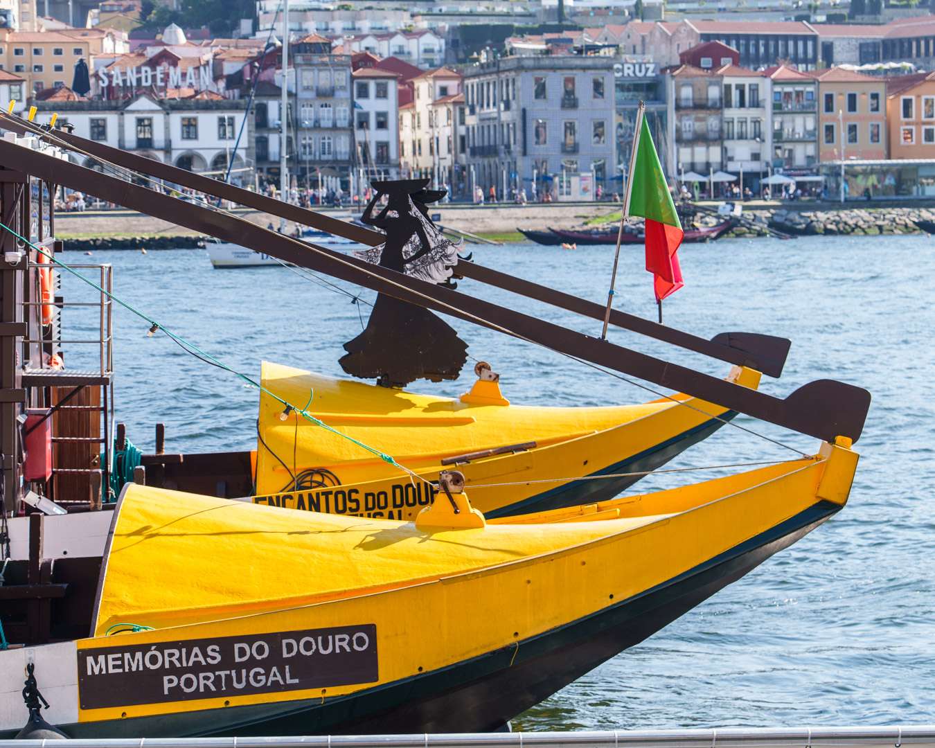 Two yellow rabelo boats with their long steering oars moored on the Gaia bank of the Douro at Porto