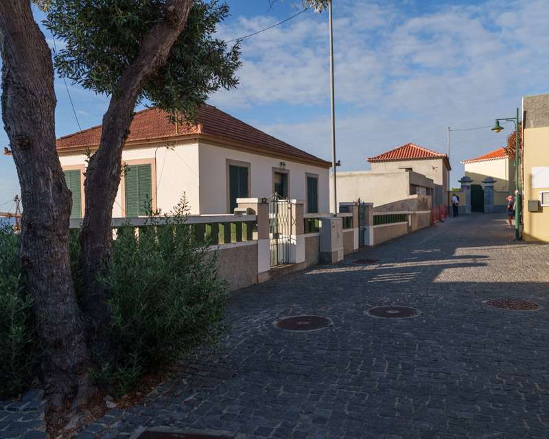 Gepflasterte Gasse in Vila Baleira mit niedrigen weißen Häusern und grünen Fensterläden