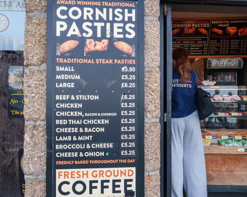 Price board for Cornish pasties beside the open door of a bakery in St Ives