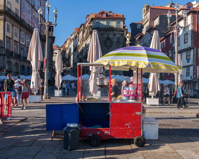 Imbisswagen mit gestreiftem Sonnenschirm auf einem Platz in der Altstadt von Porto