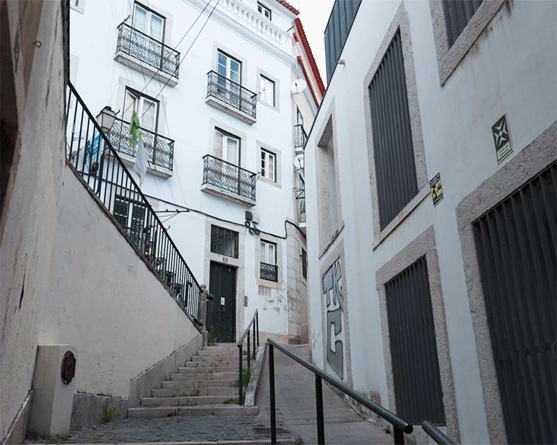 Außentreppe an einem weißen Haus der Alfama über einer steilen Gasse