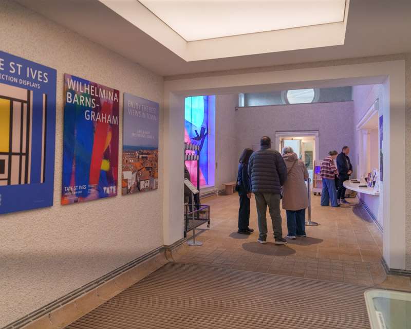 Visitors in the entrance hall of Tate St Ives with exhibition posters on the wall