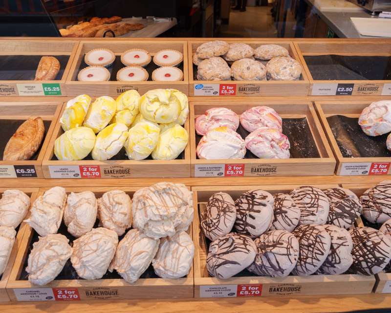 Trays of iced buns and doughnuts in a Falmouth bakery window with handwritten price cards