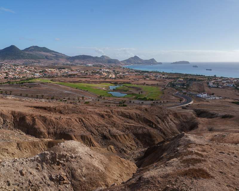 Erodierter roter Boden über dem Golfplatz von Porto Santo mit Bucht und Inselchen dahinter