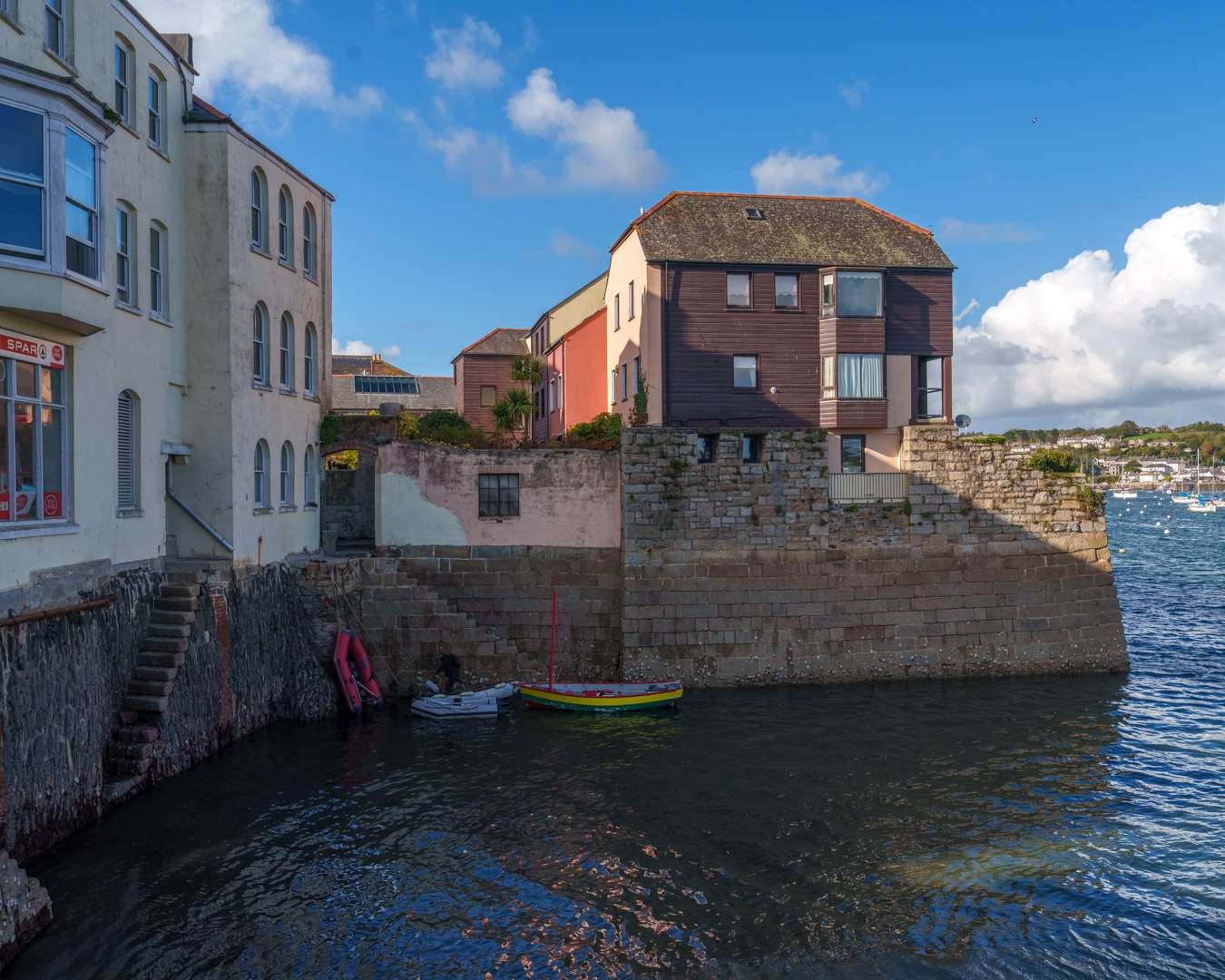 Coloured houses above the harbour wall at Falmouth with a slipway and small boats at the waterline