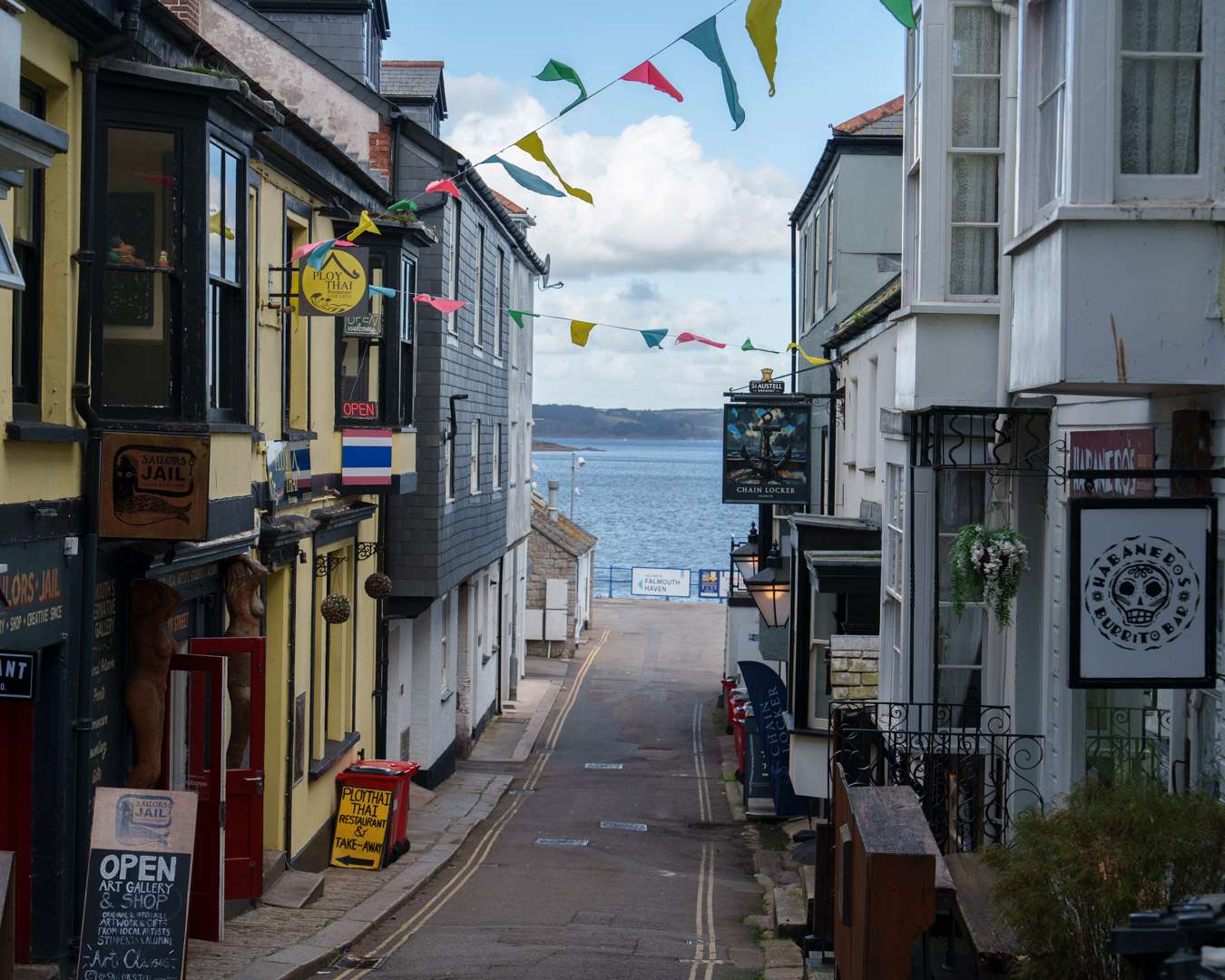 Yellow painted pub on a steep lane in Falmouth with the sea at the bottom of the street