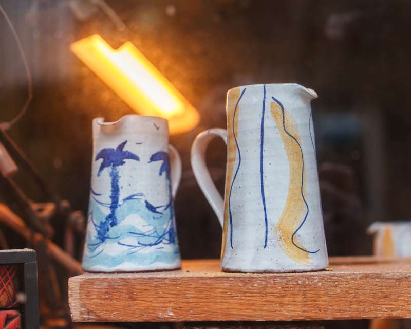 Hand-painted ceramic jugs on a shelf in a St Ives pottery